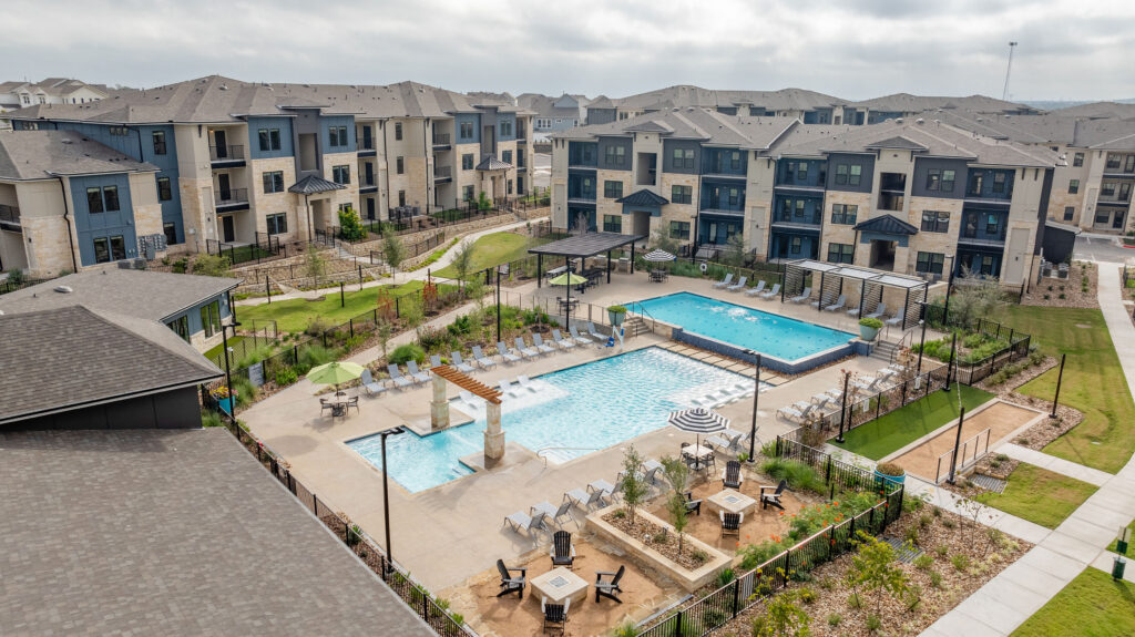 Aerial view of Residences of Siena South property including apartment buildings, pool with loungers, lap pool, cabanas, fire pit, and other onsite amenities.